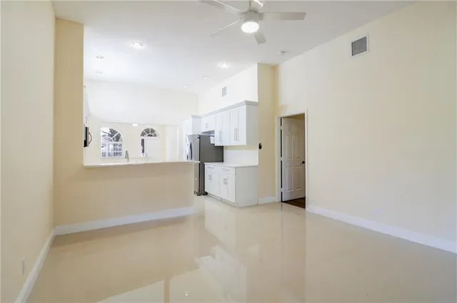 a view of a kitchen with refrigerator and white cabinets