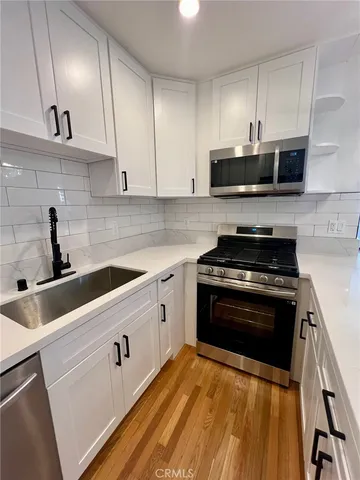 a kitchen with stainless steel appliances a sink dishwasher a stove and white cabinets
