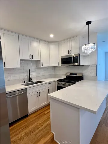 a kitchen with granite countertop a sink a stove top oven and white cabinets