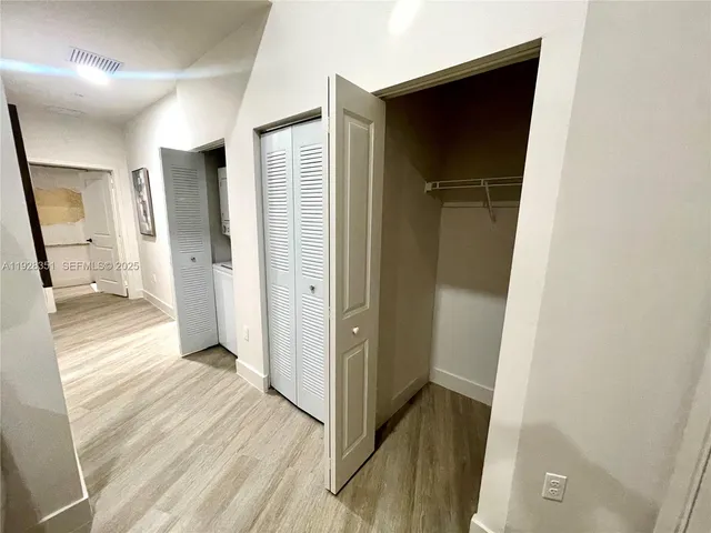 a view of a refrigerator in kitchen and an empty room