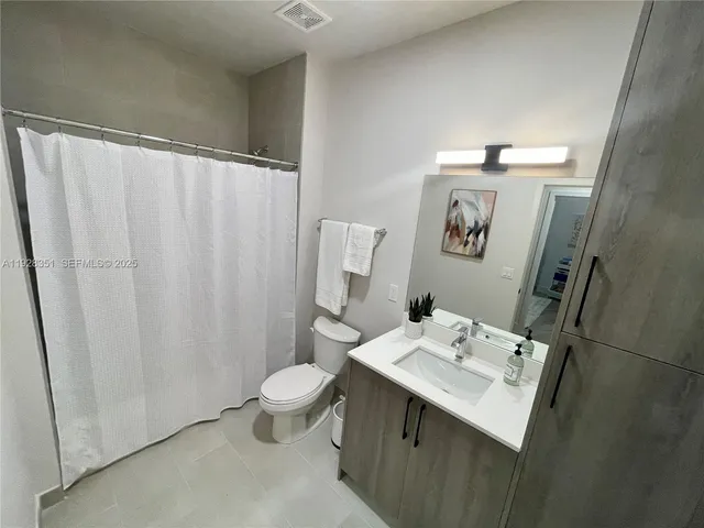 a bathroom with a sink a toilet and shower curtain