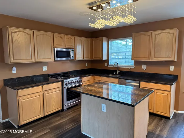 a kitchen with stainless steel appliances granite countertop a refrigerator a stove and a wooden floors