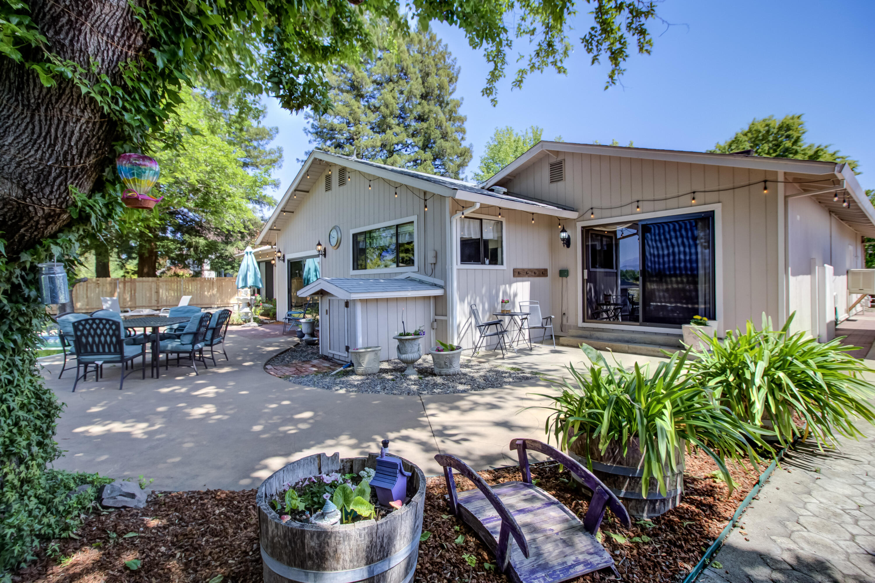 6250 Riverside Drive Redding, CA 96001 - Photo 14 of 28 a view of a patio with table and chairs potted plants and a large tree