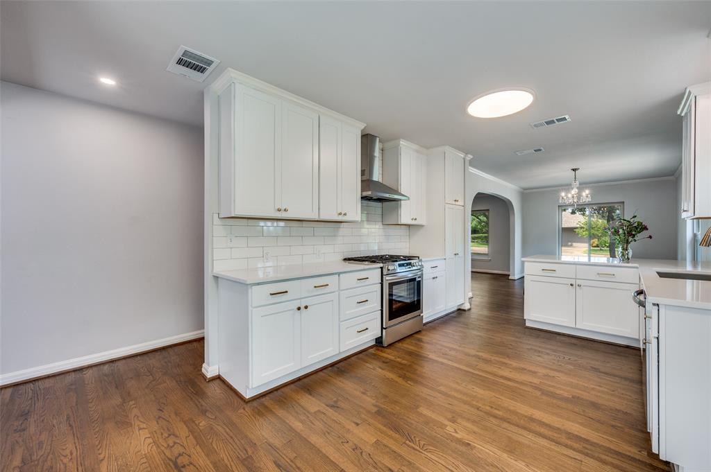 1342 Michigan Avenue Dallas, TX 75216 - Photo 14 of 25 Kitchen with arched walkways, white cabinets, decorative backsplash, stainless steel range with gas stovetop, and dark wood-style flooring