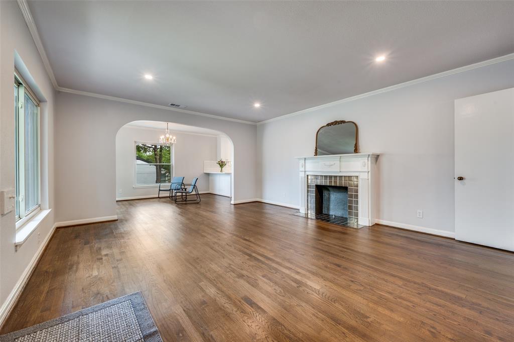 1342 Michigan Avenue Dallas, TX 75216 - Photo 8 of 25 Unfurnished living room with arched walkways, ornamental molding, a tiled fireplace, dark wood-style floors, and a chandelier