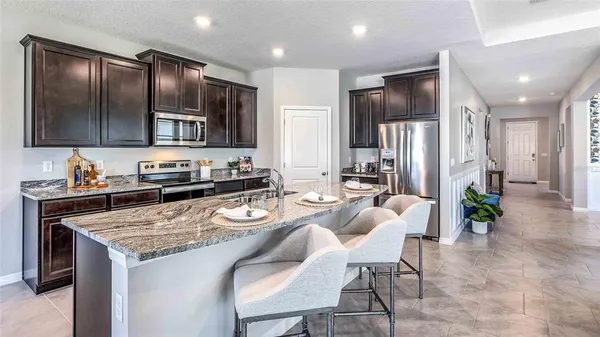 a kitchen with granite countertop stainless steel appliances a refrigerator a stove a sink and chairs