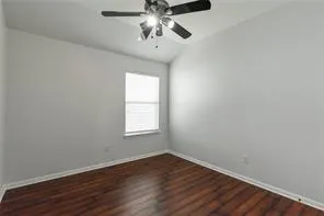 an empty room with wooden floor chandelier fan and windows