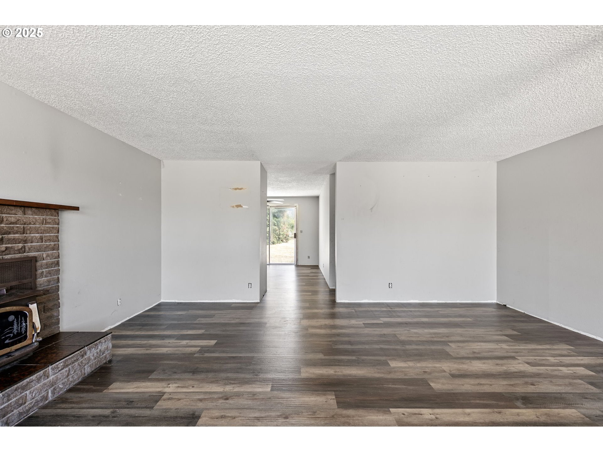 34879 Seavey Loop Road Eugene, OR 97405 - Photo 5 of 34 a view of an empty room with wooden floor and a fireplace