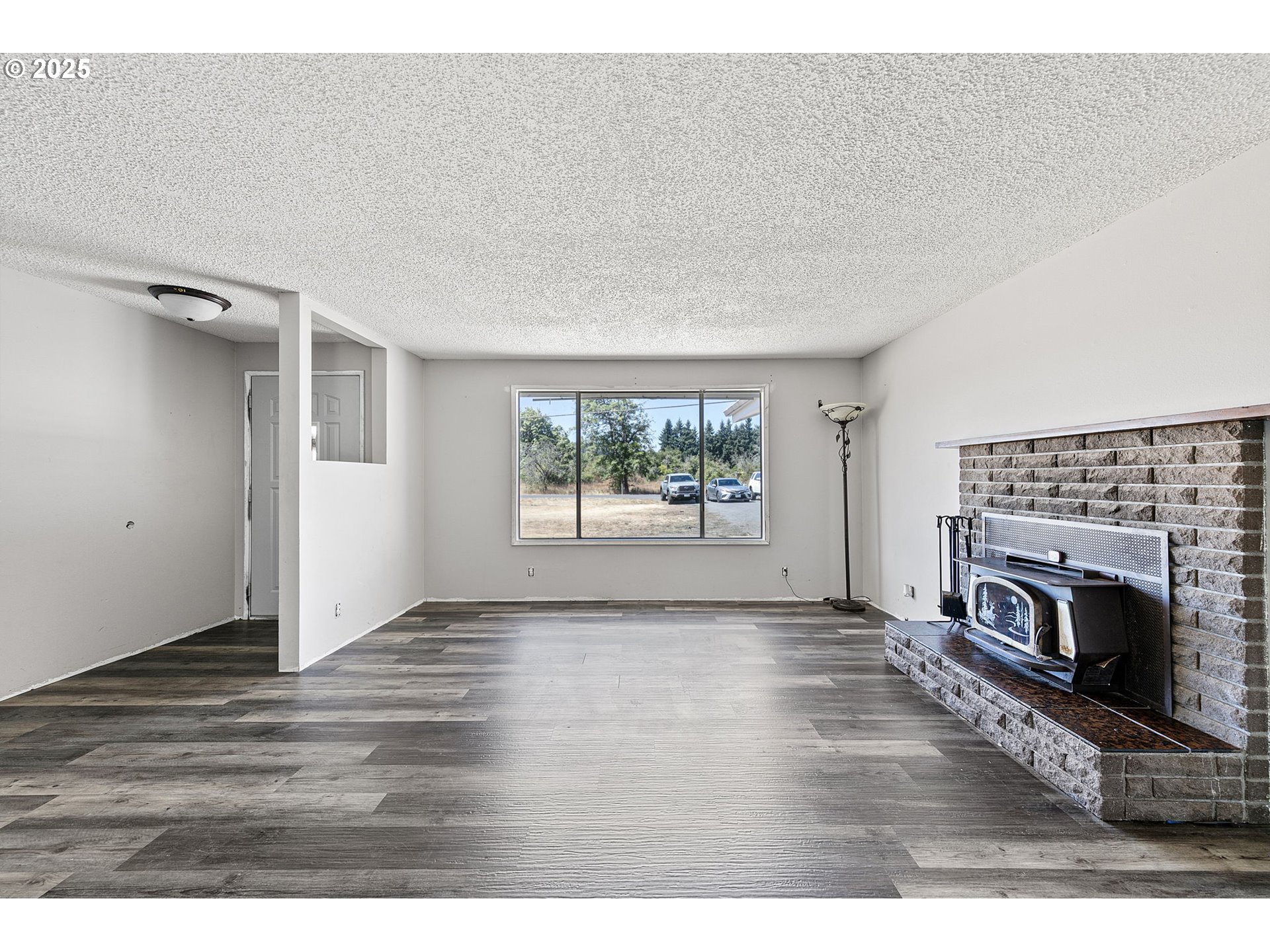 34879 Seavey Loop Road Eugene, OR 97405 - Photo 6 of 34 a view of empty room with wooden floor and fireplace