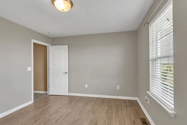 a view of an empty room with wooden floor and a window