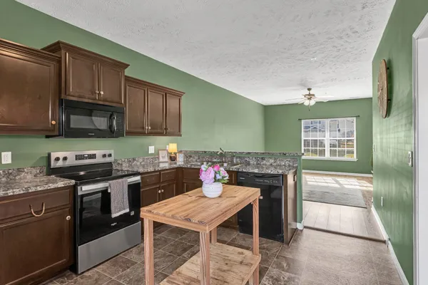 a kitchen with stainless steel appliances granite countertop a stove top oven a sink dishwasher and cabinets
