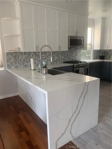 a kitchen with kitchen island granite countertop a sink a stove and cabinets