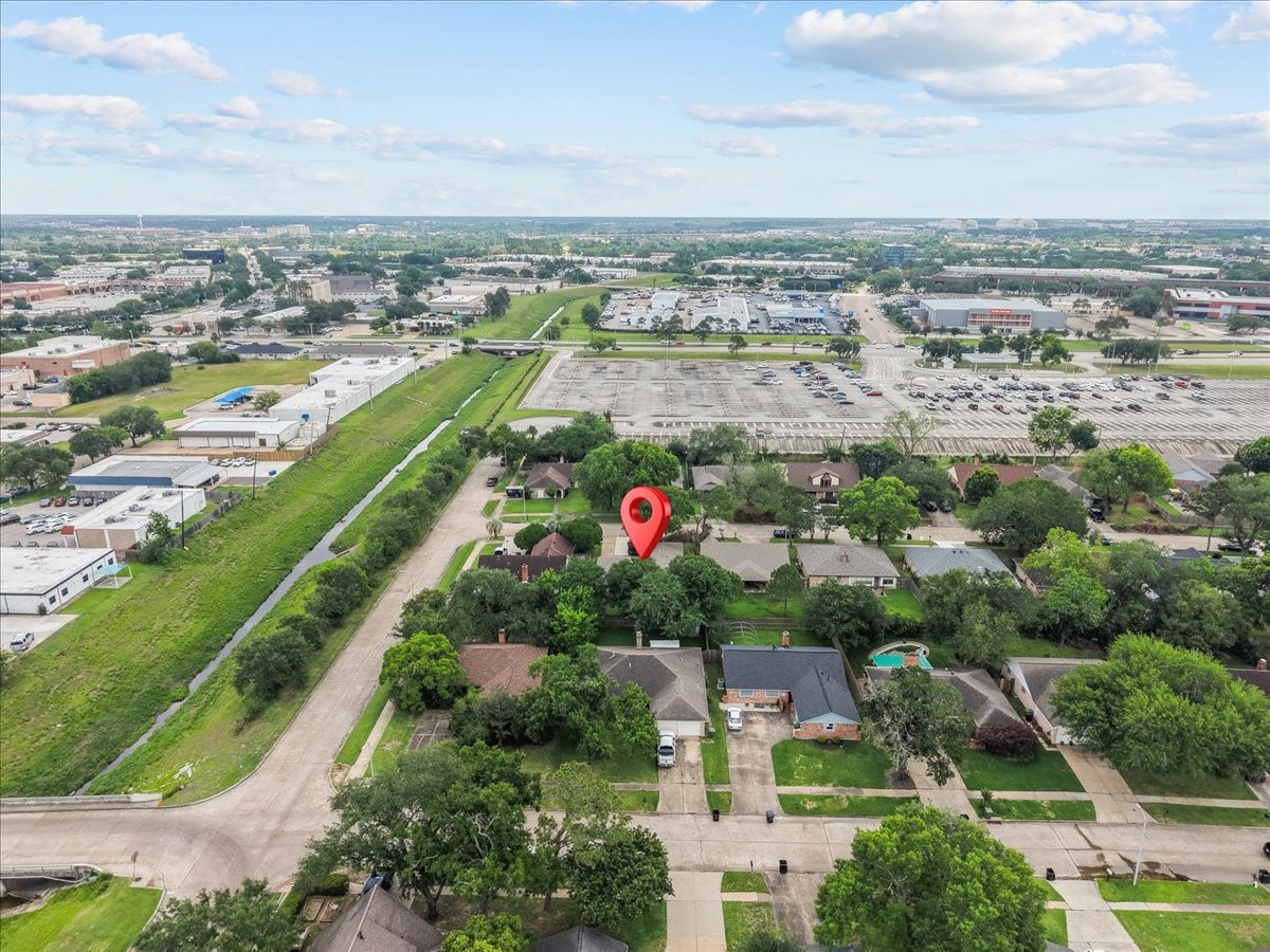 883 Silverpines Road Houston, TX 77062 - Photo 30 of 38 This aerial photo shows a suburban neighborhood with a highlighted property surrounded by greenery. The area features a mix of residential homes, nearby commercial spaces, and ample parking. There's easy access to a main road, offering convenience to shopping and other amenities.