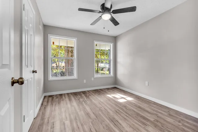 a view of empty room with wooden floor and fan