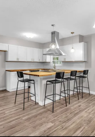 a kitchen with stainless steel appliances a table chairs in it and wooden floors