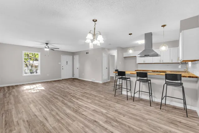 a open kitchen with stainless steel appliances granite countertop a stove top oven a dining table and chairs with wooden floor