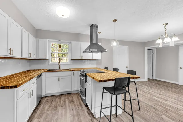 a kitchen with stainless steel appliances a stove a sink dishwasher and a refrigerator with wooden floor