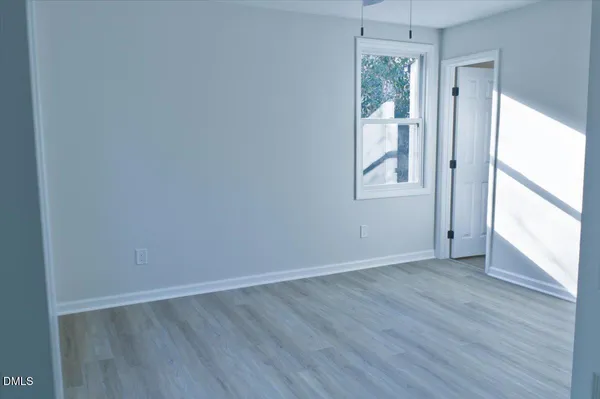 an empty room with wooden floor a ceiling fan a fireplace and windows