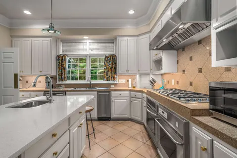 a kitchen that has a sink a stove and chairs