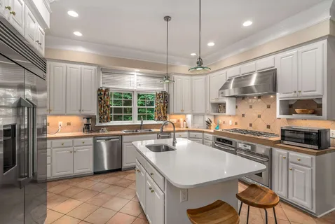 a kitchen with a sink stainless steel appliances cabinets and a large window