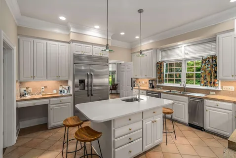 a kitchen with stainless steel appliances granite countertop a sink a stove a refrigerator cabinets and chairs