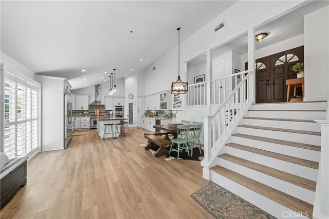 a kitchen with stainless steel appliances kitchen island granite countertop a refrigerator a stove a sink a dining table and chairs with wooden floor