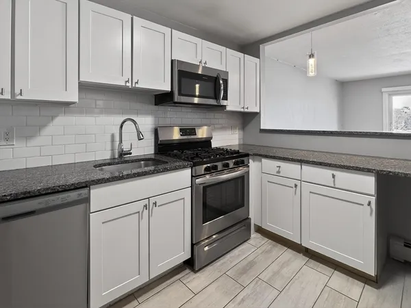 a kitchen with white cabinets and stainless steel appliances