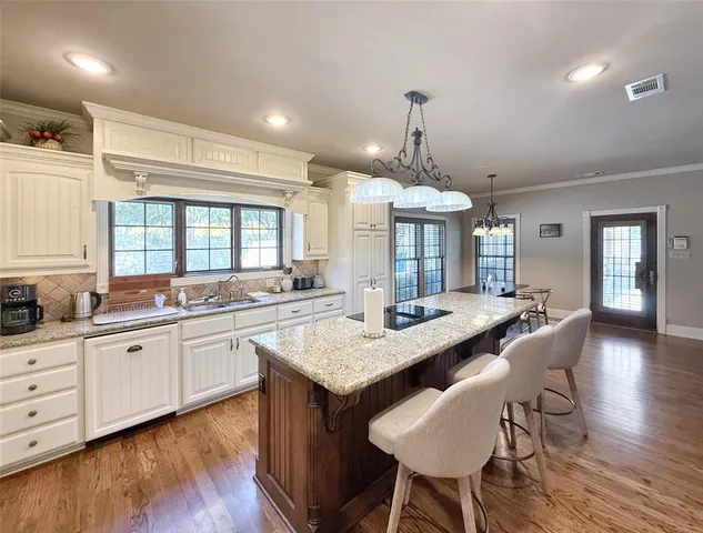 a large kitchen with granite countertop a center island a stove and a wooden floors
