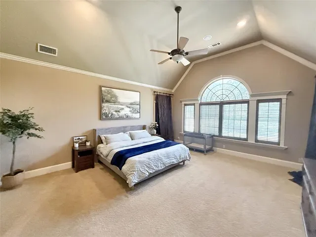a spacious bedroom with a bed a chandelier and a flat tv screen