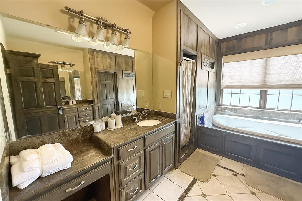 1026 Farm To Market Road 131 Denison, TX 75020 - Photo 28 of 40 a bathroom with a granite countertop double vanity sink a mirror and a bathtub