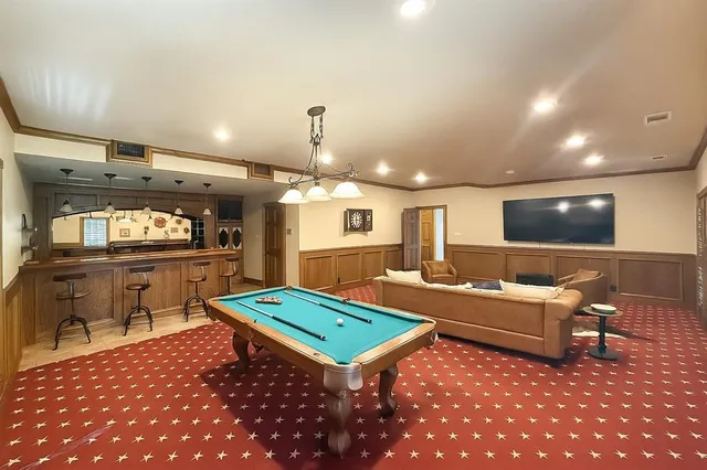 a living room with furniture pool table and flat screen tv