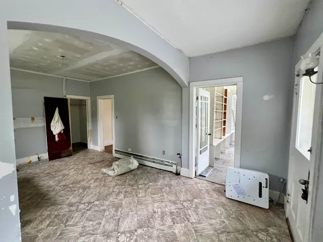 an empty room with wooden floor fireplace and windows