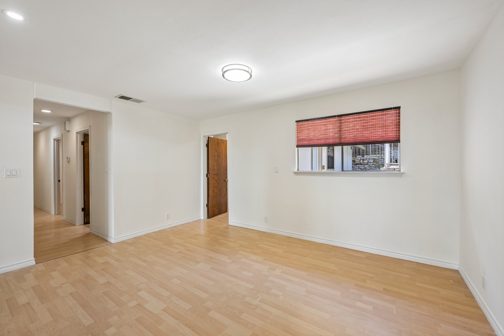 13101 Travis View Loop Austin, TX 78732 - Photo 12 of 27 Blonde wood-looking floors complement a well-lit living area, featuring a hallway leading to additional rooms.
