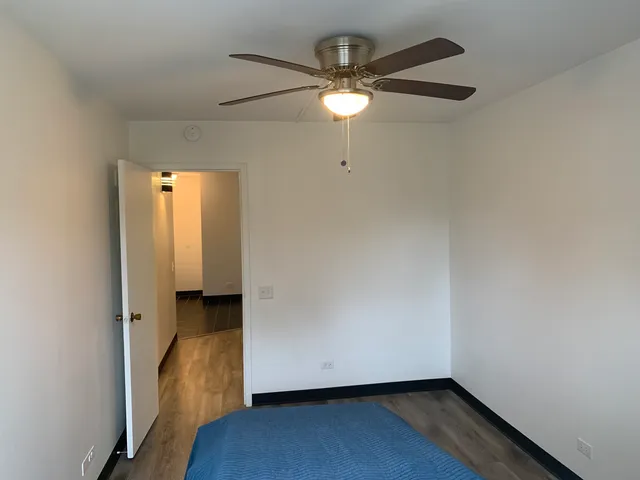 an empty room with wooden floor and fan