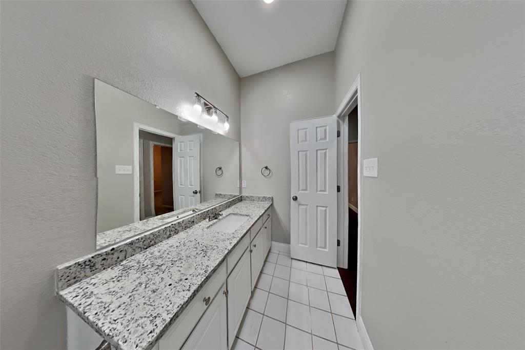 1526 Brittany Lane Mansfield, TX 76063 - Photo 16 of 18 Bathroom featuring a textured wall, vanity, and light tile patterned flooring