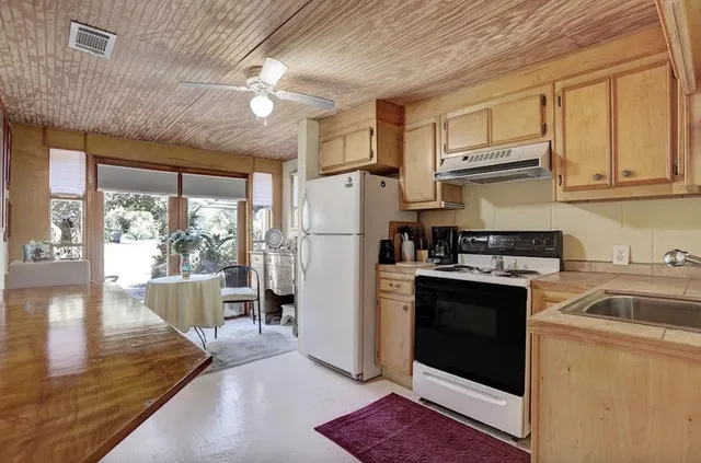 a kitchen with stainless steel appliances granite countertop a refrigerator a stove a sink dishwasher and white cabinets with wooden floor