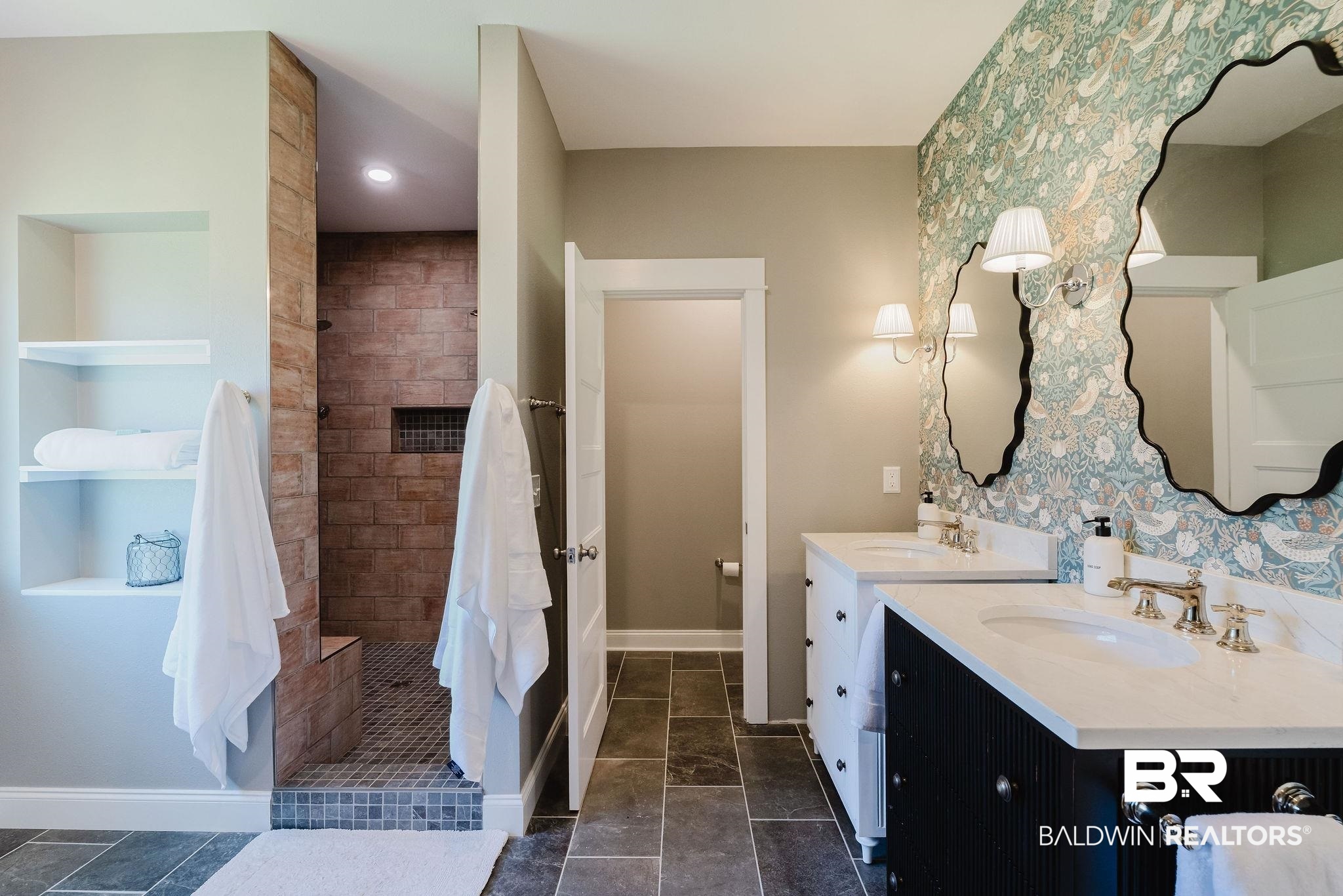 7872 Calverton Street Foley, AL 36535 - Photo 18 of 76 Bathroom featuring a dual vanity with white countertops and undermount sinks, patterned wallpaper, slate-style floor tiling, and a tiled shower with a built-in bench