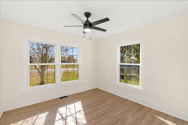 a view of an empty room with a window and wooden floor