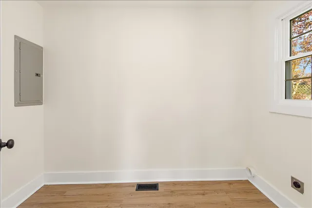 a view of an empty room with wooden floor and a window