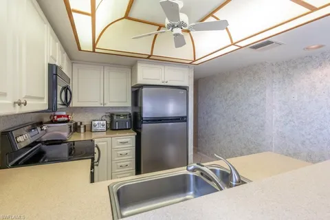 a kitchen with stainless steel appliances granite countertop a sink a stove top oven a chimney and a refrigerator