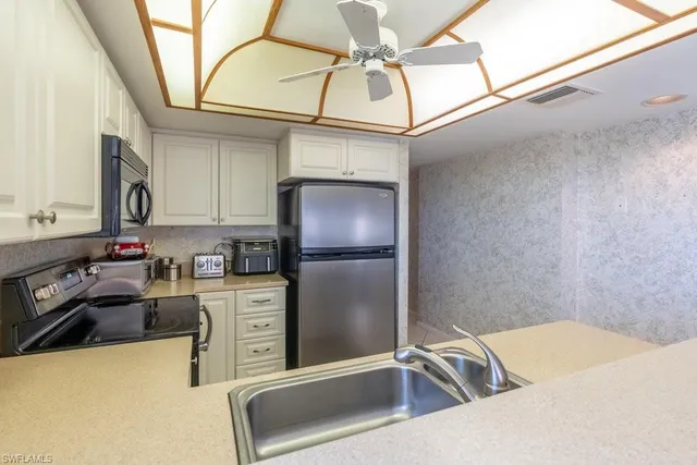a kitchen with stainless steel appliances granite countertop a sink a stove top oven a chimney and a refrigerator