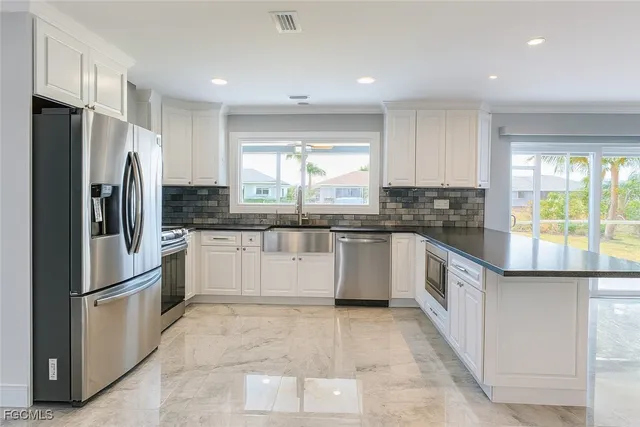 a kitchen with granite countertop a refrigerator and white cabinets