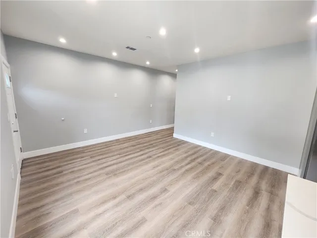 an empty room with wooden floor and entrance