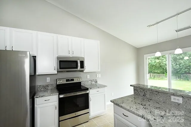 a kitchen with granite countertop a stove a microwave a refrigerator a sink and dishwasher with wooden floor