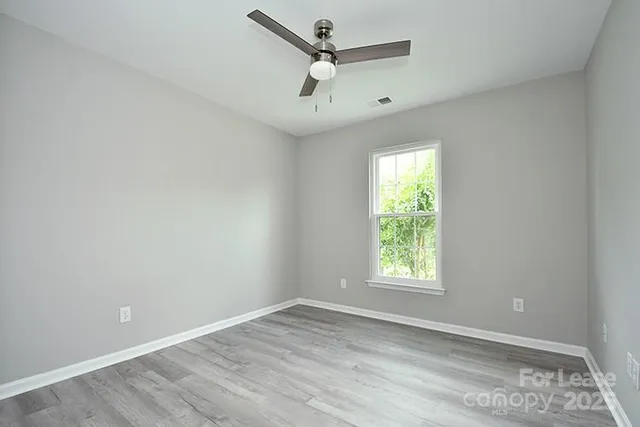 an empty room with windows and ceiling fan