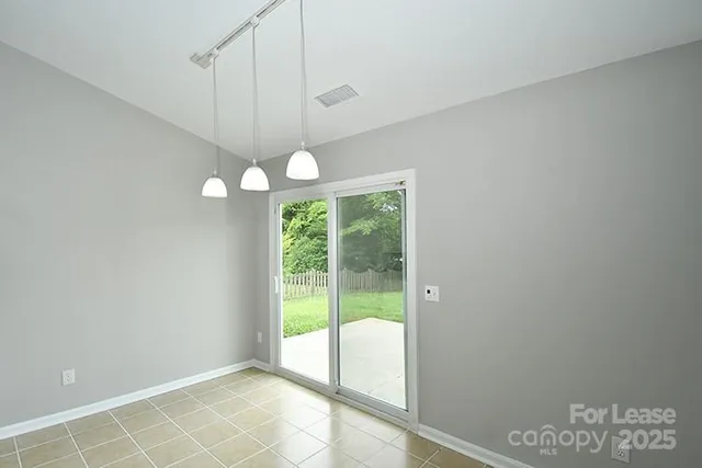 a view of an empty room with window and chandelier fan
