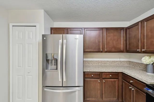 a kitchen with stainless steel appliances granite countertop a refrigerator a stove and a sink with wooden floor