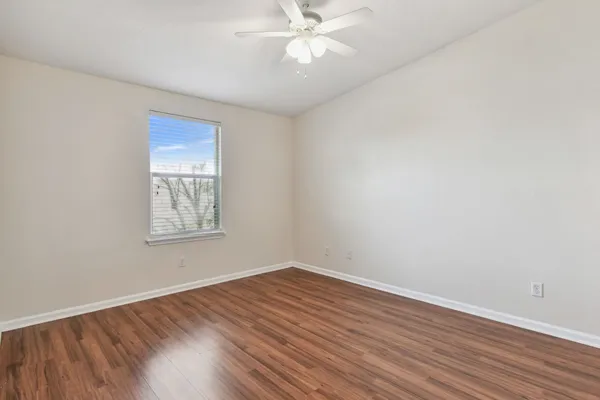 an empty room with wooden floor and a ceiling fan