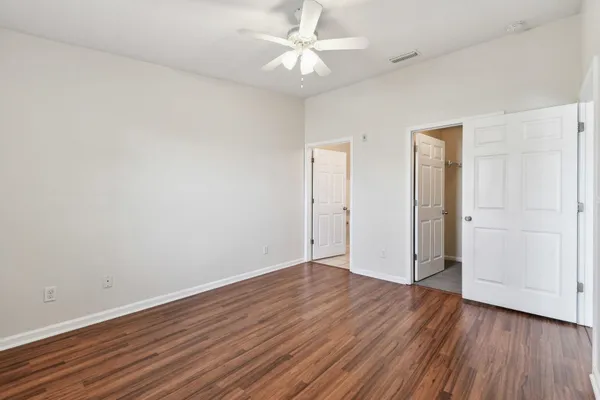 an empty room with wooden floor and a ceiling fan