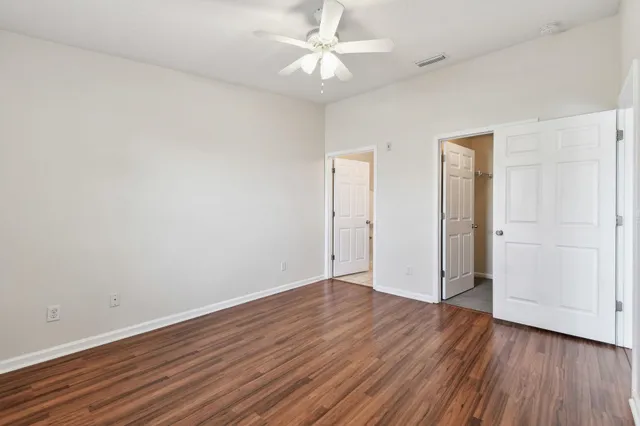 an empty room with wooden floor and a ceiling fan